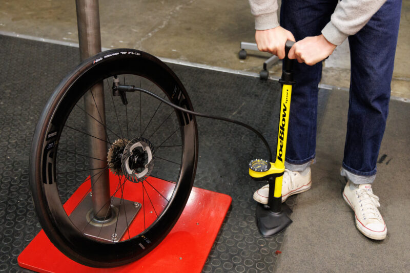 Una persona que utiliza una bomba de piso para inflar el neumático de una bicicleta.