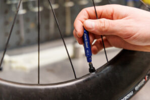 Una persona que utiliza una herramienta de extracción de núcleos de válvulas para instalar neumáticos nuevos de bicicleta.