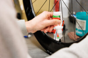 Un hombre añadiendo sellador de neumáticos a una rueda de bicicleta.